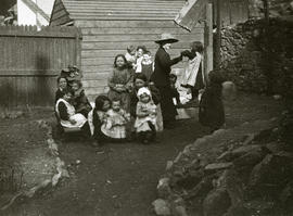 Group of children in backcourt garden with well-dressed woman
